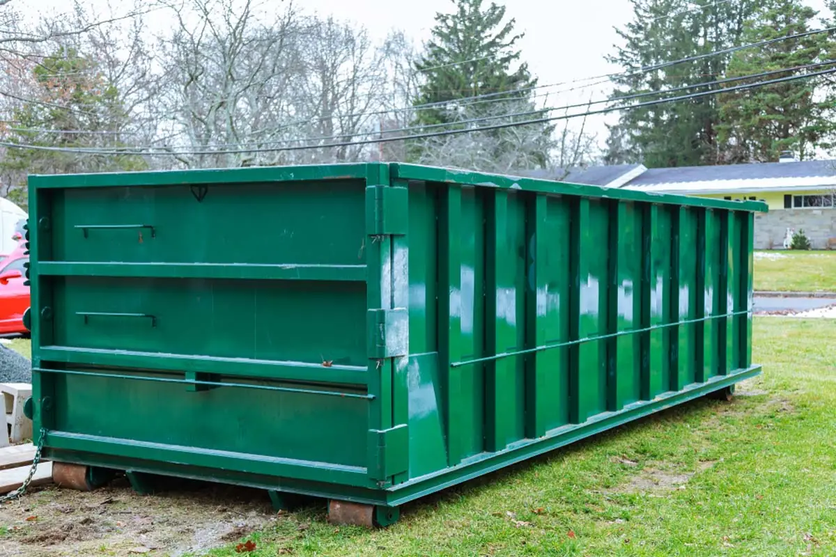 Roll-off dumpster in a residential yard for a home cleanout