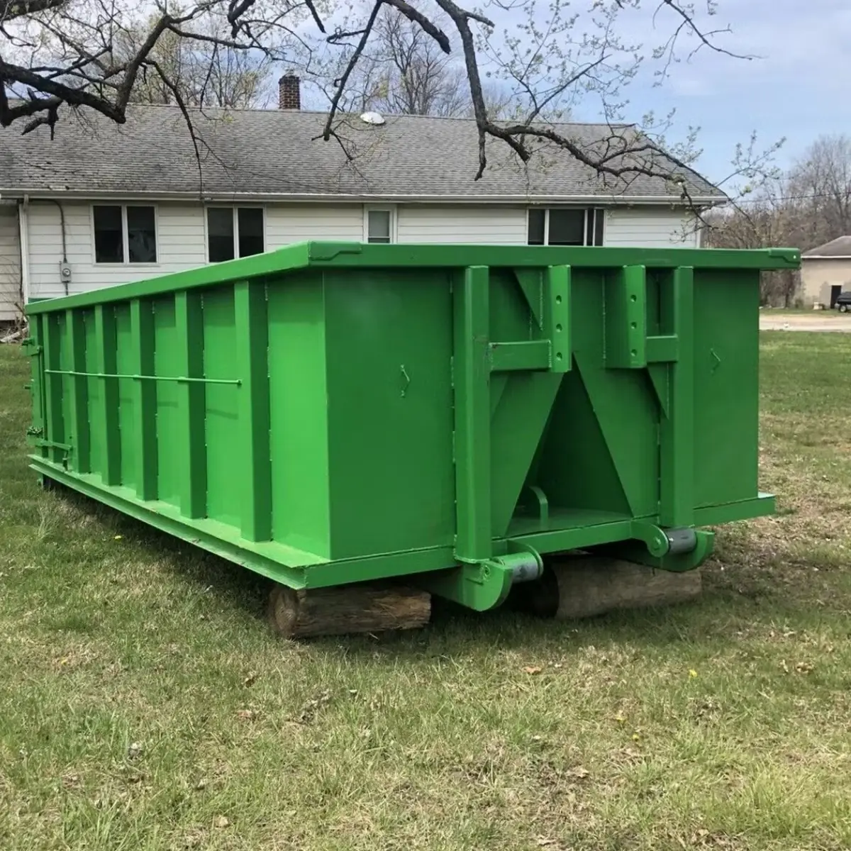 Roll-off dumpster resting on boards in a residential yard