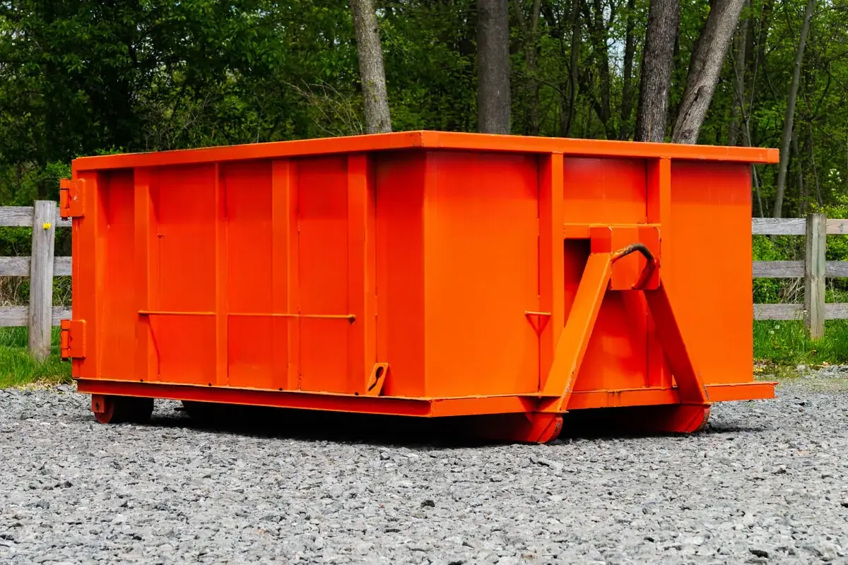Orange roll-off dumpster with a rear door, ready for roofing debris